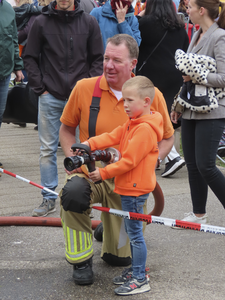 902344 Afbeelding van lid van de vrijwillige brandweer die een jongetje kinderen begeleidt bij het spuiten op een doel, ...